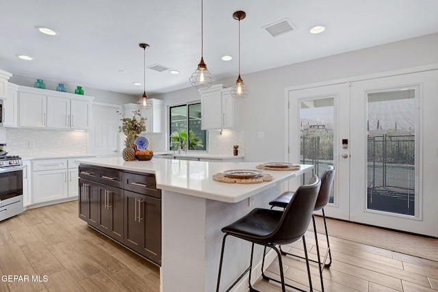 kitchen featuring gas range, light countertops, white cabinetry, light wood finished floors, and recessed lighting