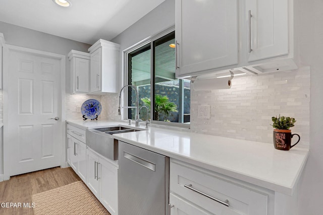 kitchen with dishwasher, backsplash, a sink, white cabinets, and recessed lighting