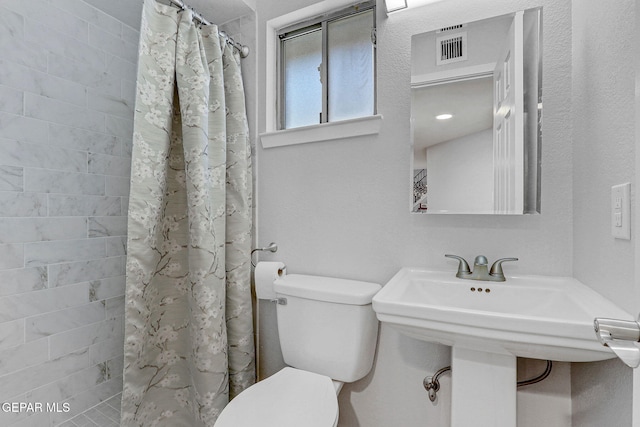 bathroom featuring toilet and tiled shower