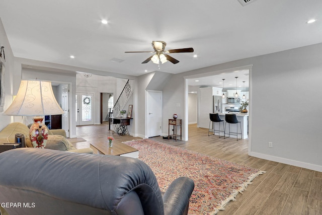 living area with a ceiling fan, light wood-type flooring, baseboards, recessed lighting, and stairway