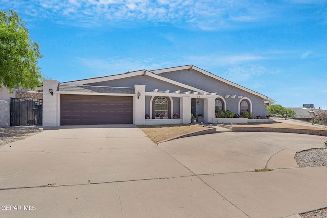 view of front facade with concrete driveway, a garage, brick siding, and fence