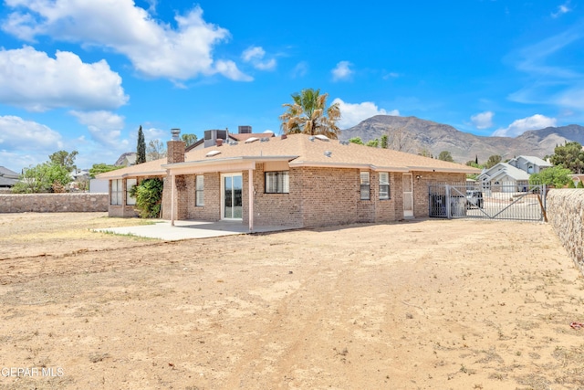 rear view of property featuring a patio, a gate, a mountain view, brick siding, and fence