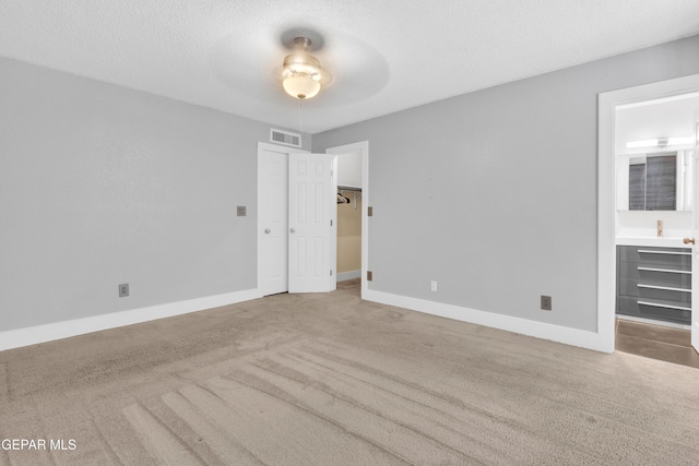 unfurnished bedroom with carpet floors, baseboards, ensuite bath, and a ceiling fan