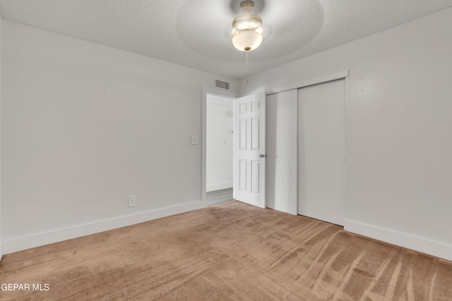 unfurnished bedroom featuring carpet flooring, a closet, a textured ceiling, a ceiling fan, and baseboards
