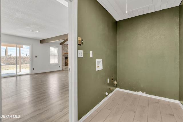 laundry area with wood finished floors, baseboards, washer hookup, and a fireplace