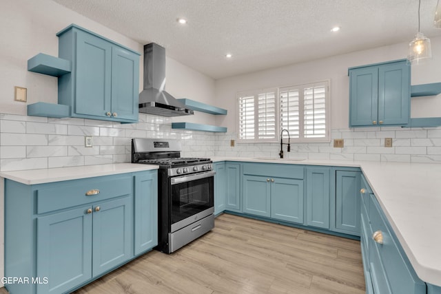 kitchen featuring open shelves, stainless steel range with gas cooktop, blue cabinets, a sink, and a textured ceiling