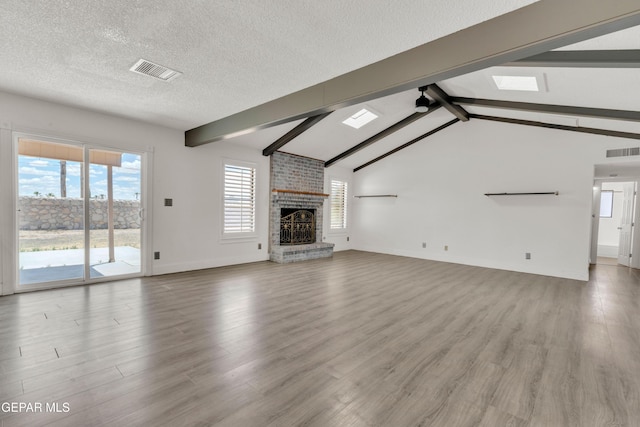 unfurnished living room with wood finished floors, a brick fireplace, baseboards, and a textured ceiling