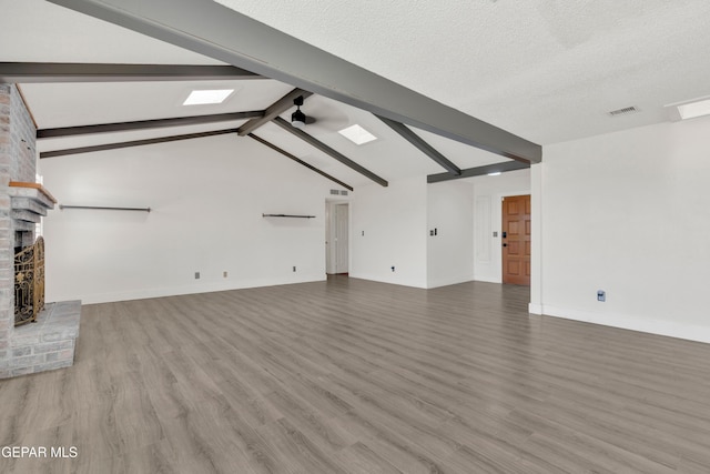 unfurnished living room with wood finished floors, a fireplace, baseboards, a skylight, and a textured ceiling