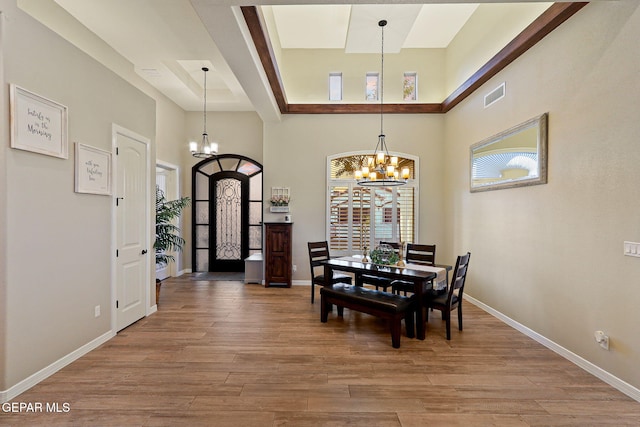 dining space with a chandelier, a high ceiling, light wood finished floors, and baseboards