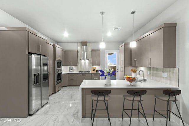12627 Naes Way, El Paso, TX 79928 - kitchen featuring stainless steel appliances, a peninsula, decorative backsplash, wall chimney range hood, and a kitchen bar