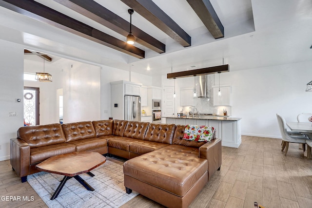 living room featuring beamed ceiling, light wood-style flooring, baseboards, a chandelier, and a ceiling fan