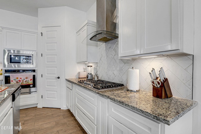 kitchen with wall chimney exhaust hood, appliances with stainless steel finishes, and white cabinets