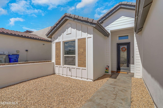 doorway to property with a tiled roof and board and batten siding