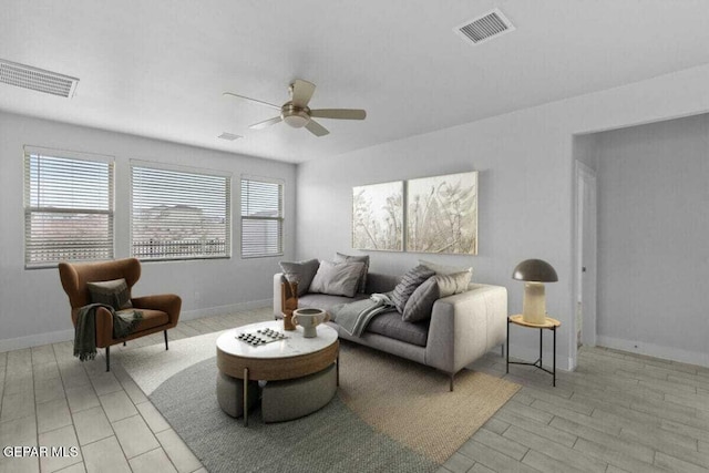 living room featuring a ceiling fan, baseboards, and light wood finished floors