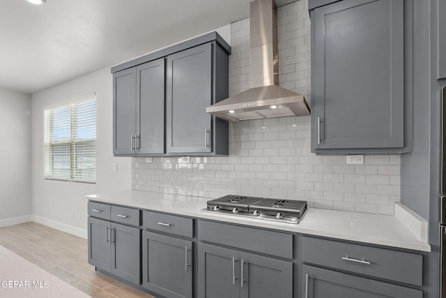 7461 Big Mountain Ct, El Paso, TX 79911 - kitchen featuring gray cabinetry, wall chimney exhaust hood, baseboards, stainless steel gas stovetop, and decorative backsplash