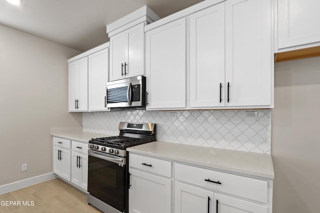 7465 Big Mountain Ct, El Paso, TX 79911 - kitchen with stainless steel appliances, baseboards, backsplash, and white cabinets