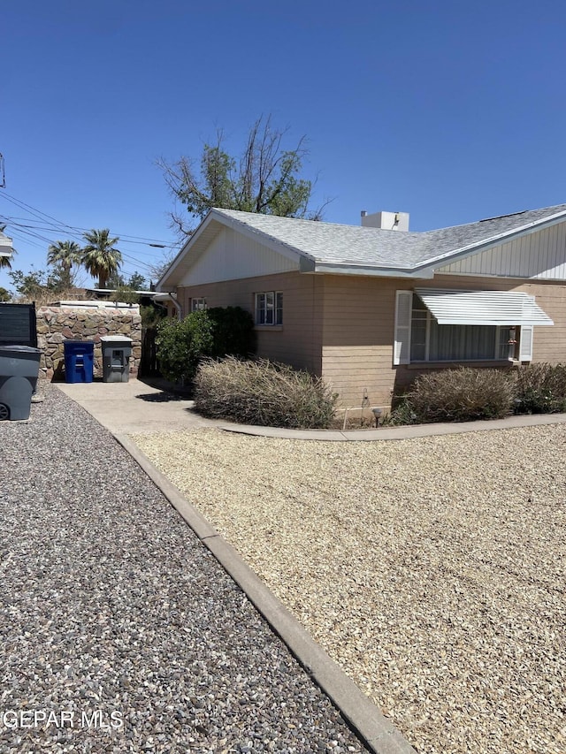 view of property exterior with brick siding and roof with shingles
