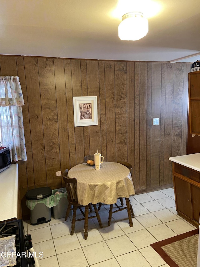 dining space with wood walls and light tile patterned floors