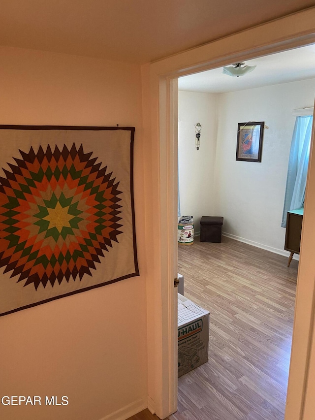 corridor with wood finished floors and baseboards