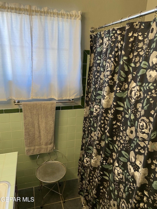 bathroom featuring tile walls, a shower with curtain, tile patterned floors, and a sink