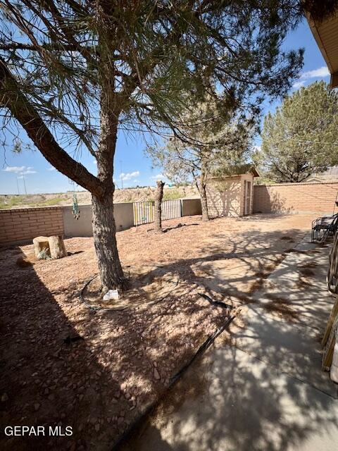 fenced backyard featuring a storage unit, an outdoor structure, and a patio area