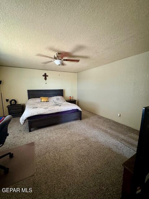 carpeted bedroom featuring a textured ceiling and a ceiling fan