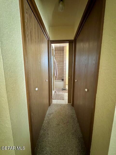 hall with a textured wall and tile patterned flooring
