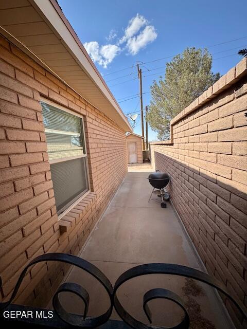view of property exterior with brick siding, a patio area, and fence