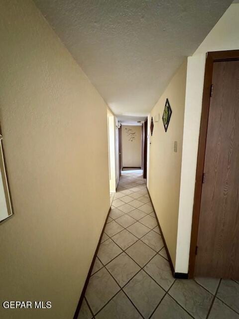 hall with light tile patterned floors and a textured ceiling