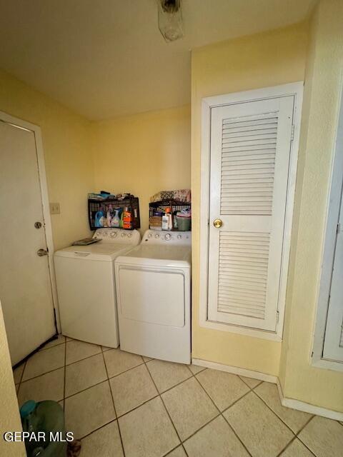 laundry area with washing machine and dryer and light tile patterned floors