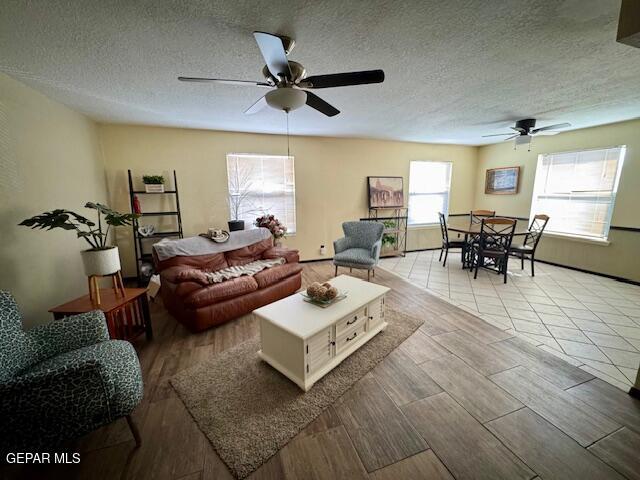 living room with ceiling fan, a textured ceiling, and wood finished floors