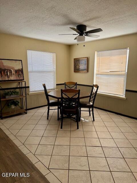 dining space with a textured ceiling, a ceiling fan, and light tile patterned floors