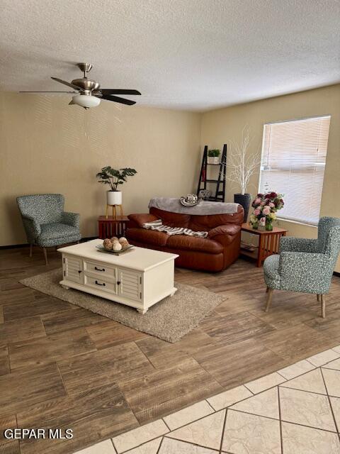 living area featuring a ceiling fan, a textured ceiling, and light wood-style floors