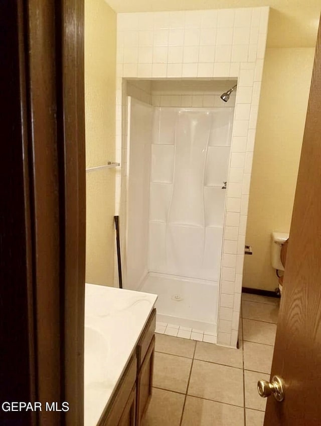 bathroom with tile patterned floors, a shower, and vanity