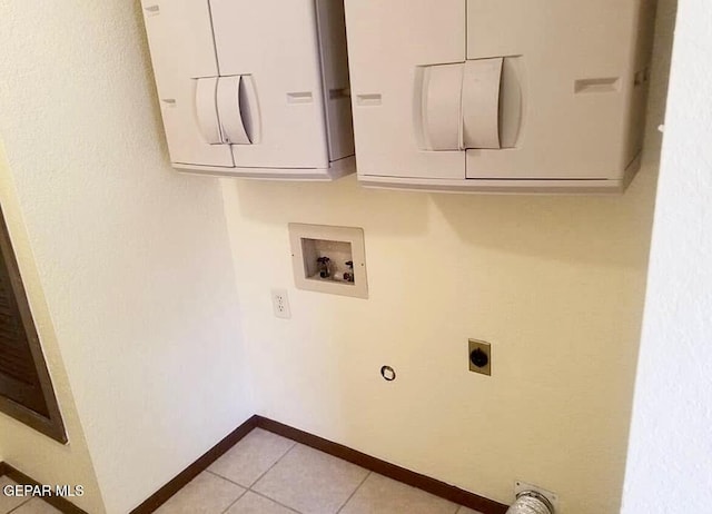 washroom with electric dryer hookup, washer hookup, baseboards, light tile patterned floors, and cabinet space