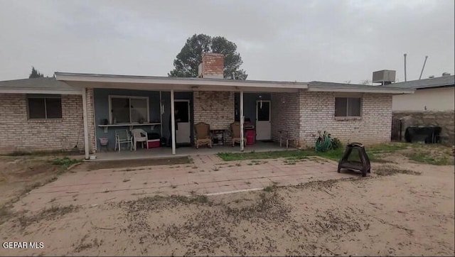 3433 Dialrock Ln, El Paso, TX 79935 - rear view of house with a chimney, a patio, and brick siding