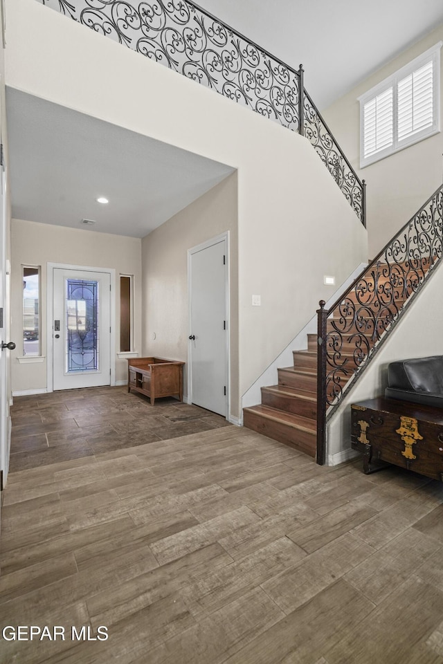 entryway with stairway, wood finished floors, a towering ceiling, and recessed lighting