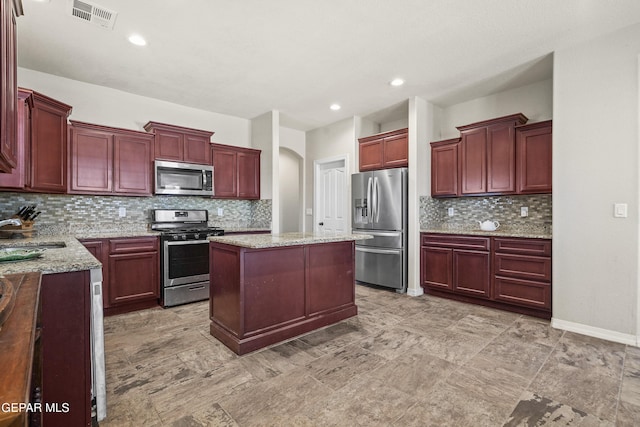 kitchen with appliances with stainless steel finishes, reddish brown cabinets, a sink, decorative backsplash, and recessed lighting