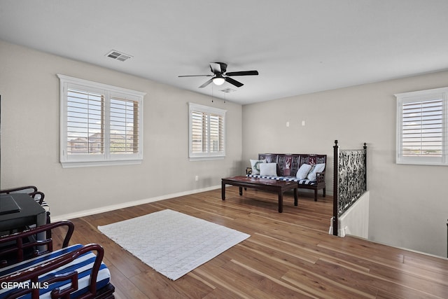 sitting room with a ceiling fan, wood finished floors, and baseboards