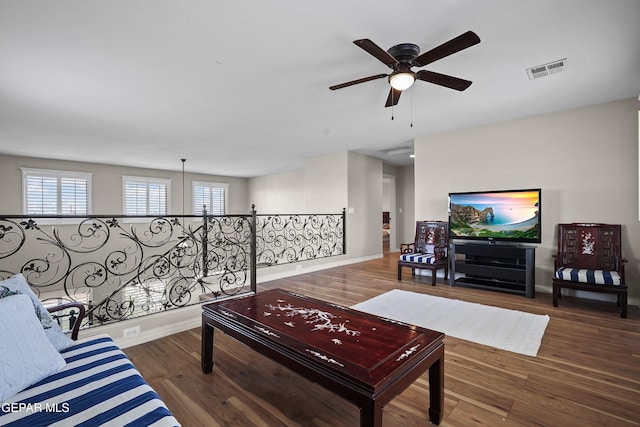 living room with ceiling fan, baseboards, and wood finished floors