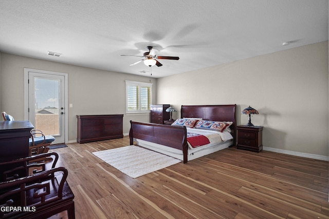bedroom featuring access to outside, wood finished floors, baseboards, and a ceiling fan