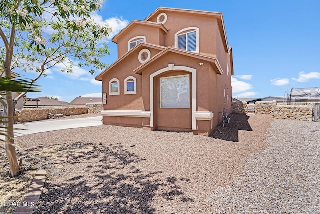 view of front facade with stucco siding and fence