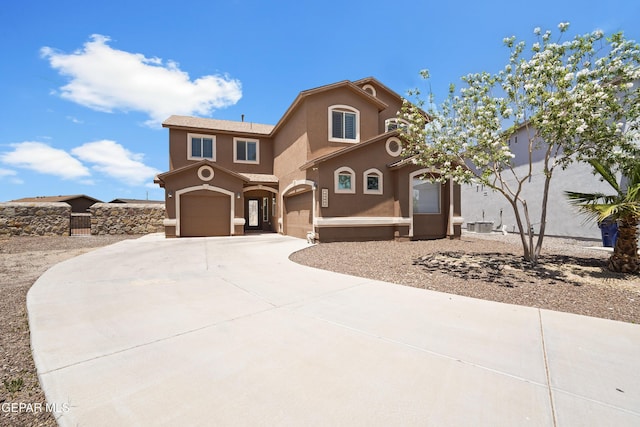 mediterranean / spanish house with stucco siding, an attached garage, and concrete driveway