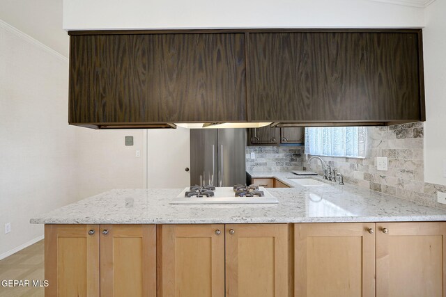 kitchen with a sink, white gas cooktop, freestanding refrigerator, a peninsula, and crown molding