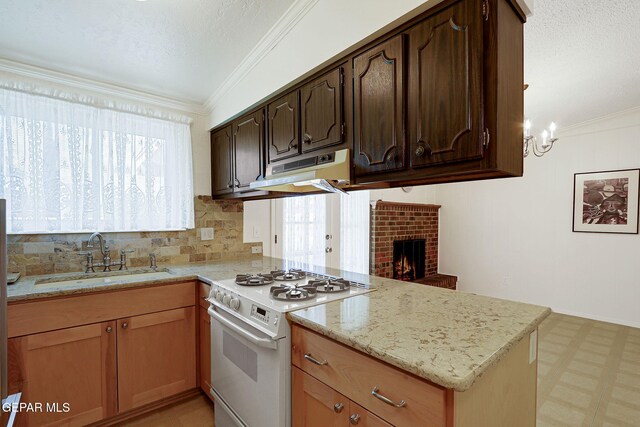 kitchen with white gas range oven, under cabinet range hood, a sink, a peninsula, and light floors