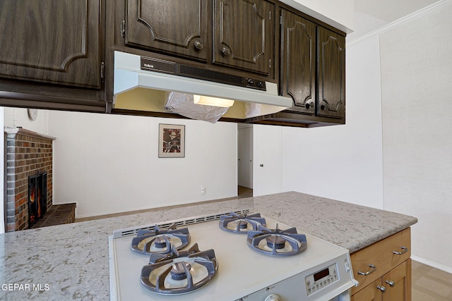 kitchen with under cabinet range hood, dark brown cabinets, white range with gas stovetop, and a fireplace