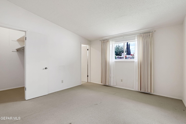 carpeted empty room with a textured ceiling and baseboards