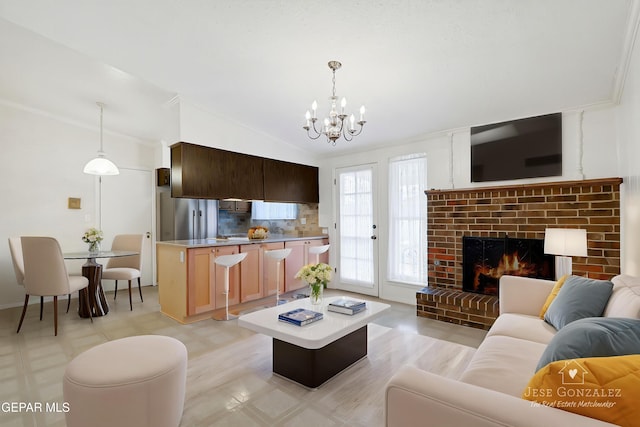 living area with a chandelier, lofted ceiling, crown molding, a fireplace, and light flooring