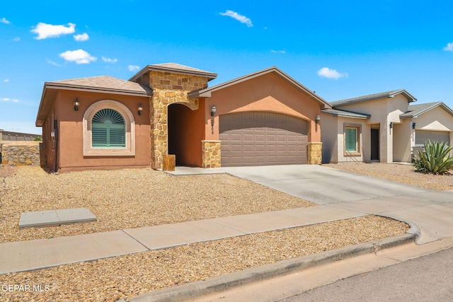 mediterranean / spanish home featuring an attached garage, stone siding, driveway, and stucco siding