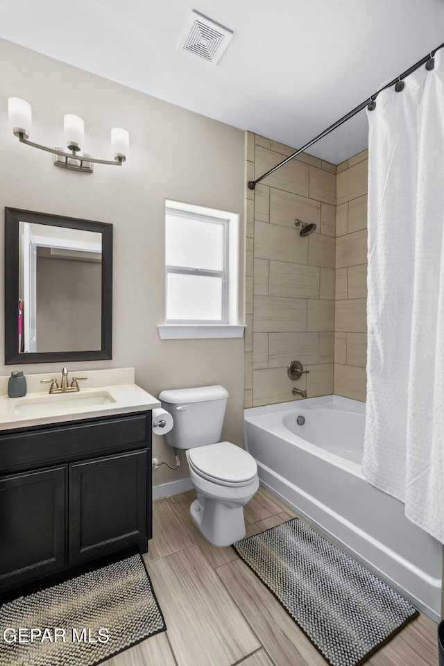bathroom featuring toilet, shower / bath combo with shower curtain, baseboards, and vanity